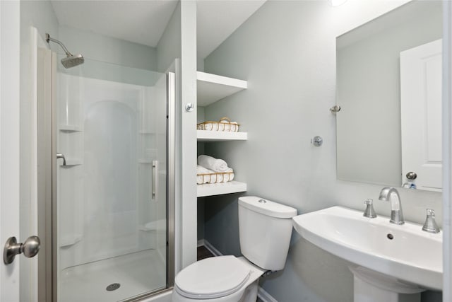 bathroom with toilet, a shower with door, and sink