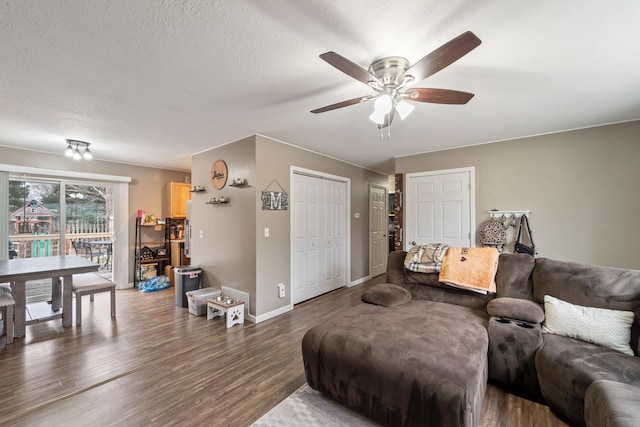 living room with ceiling fan, dark hardwood / wood-style floors, and a textured ceiling