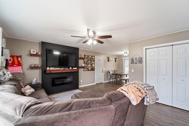 living room featuring dark hardwood / wood-style flooring, a large fireplace, and ceiling fan