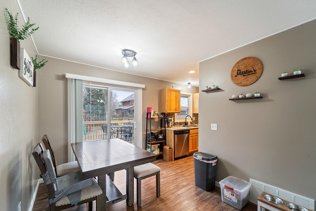 dining room featuring sink, hardwood / wood-style flooring, and a textured ceiling