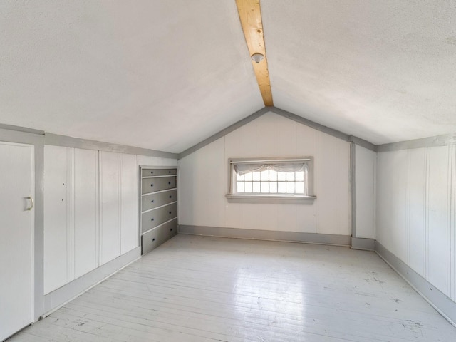 additional living space with lofted ceiling, a textured ceiling, and light wood-type flooring