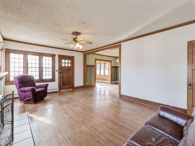 living room with ornamental molding, a baseboard heating unit, ceiling fan, light hardwood / wood-style floors, and a textured ceiling