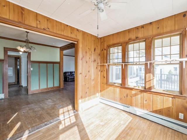 interior space with a baseboard radiator, wood-type flooring, ceiling fan with notable chandelier, and wooden walls