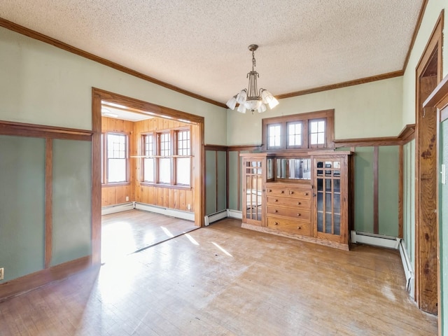 interior space with crown molding, a notable chandelier, plenty of natural light, and a baseboard heating unit