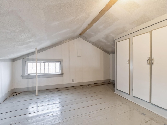 additional living space with lofted ceiling, light hardwood / wood-style floors, and a textured ceiling