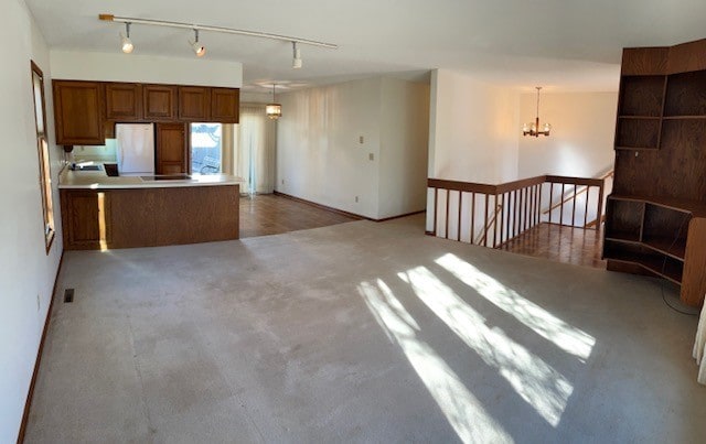 kitchen with hanging light fixtures, fridge, a chandelier, and kitchen peninsula