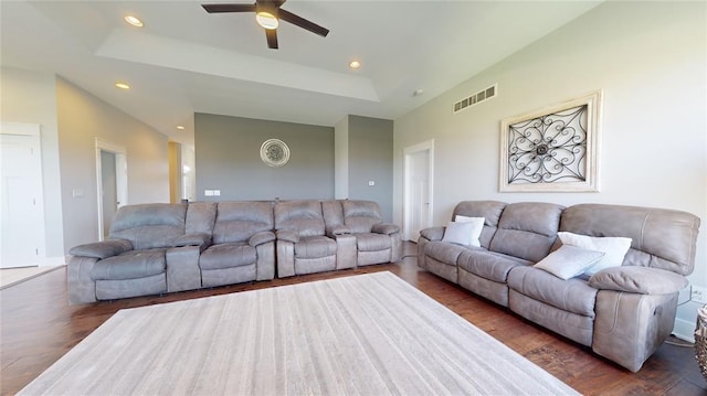 living room with ceiling fan, a tray ceiling, and dark hardwood / wood-style flooring