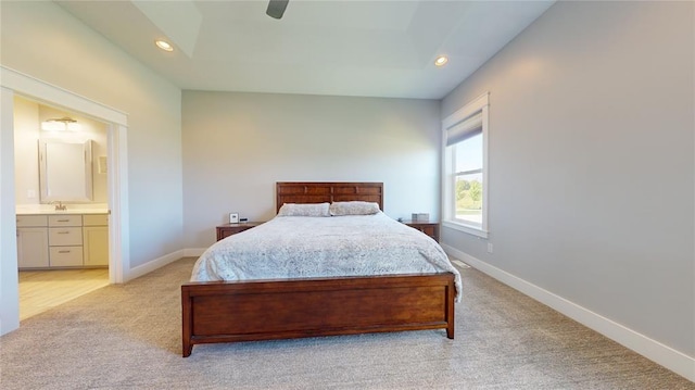 carpeted bedroom with ceiling fan, connected bathroom, and a tray ceiling