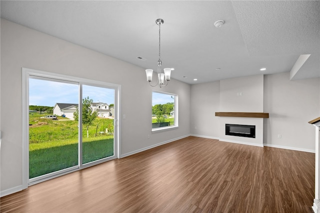 unfurnished living room featuring an inviting chandelier and hardwood / wood-style floors