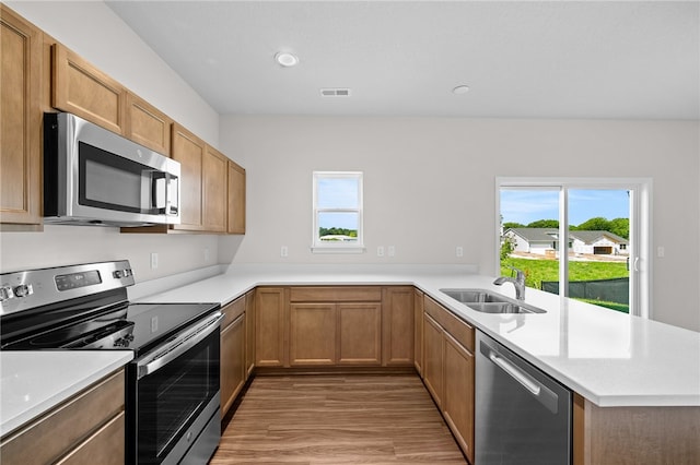 kitchen featuring stainless steel appliances, hardwood / wood-style flooring, sink, and kitchen peninsula