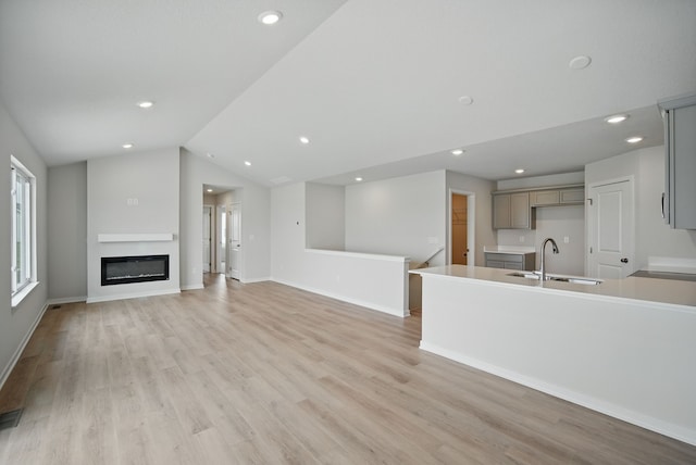 unfurnished living room with recessed lighting, a sink, and light wood-type flooring
