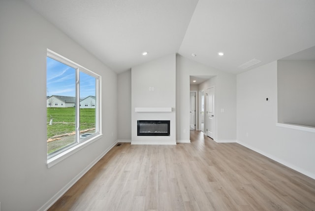 unfurnished living room featuring a glass covered fireplace, light wood-style floors, vaulted ceiling, and baseboards