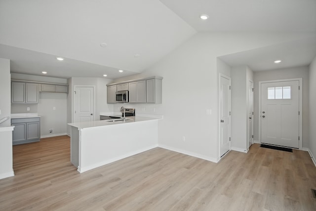 kitchen featuring gray cabinets, a peninsula, stainless steel appliances, and light wood-style floors