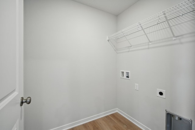 clothes washing area with wood finished floors, laundry area, hookup for an electric dryer, washer hookup, and baseboards