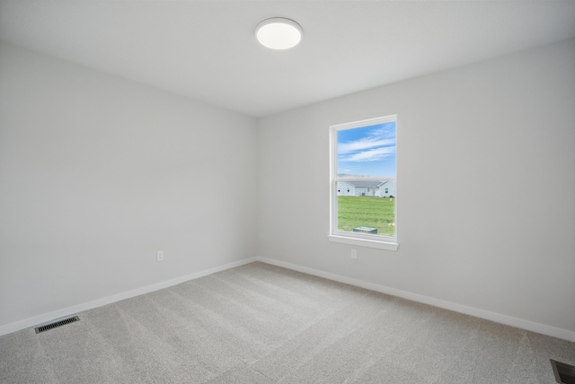 empty room featuring visible vents, light colored carpet, and baseboards