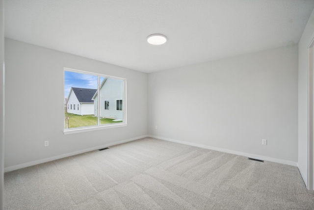 empty room featuring visible vents, carpet, and baseboards