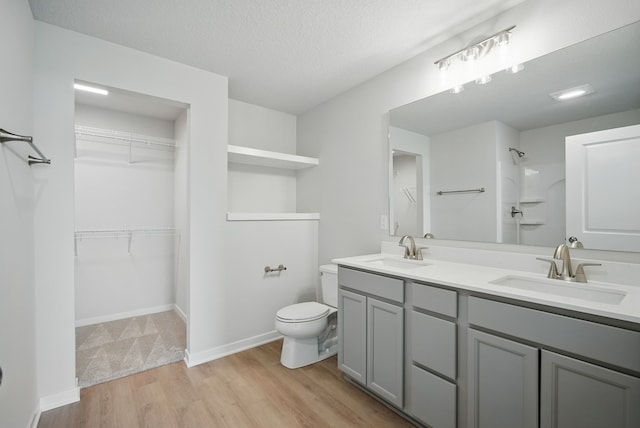 full bathroom featuring a shower, wood finished floors, toilet, and a sink