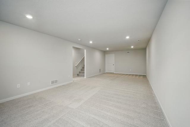 basement with visible vents, recessed lighting, light carpet, and stairs