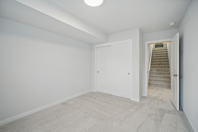 unfurnished bedroom featuring a closet, baseboards, and light carpet