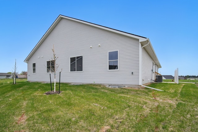 rear view of property featuring a lawn and central air condition unit
