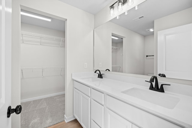 full bath featuring double vanity, baseboards, visible vents, and a sink