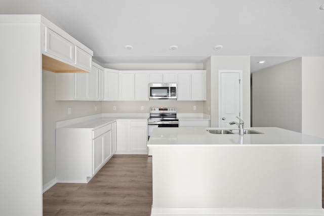 kitchen featuring white cabinets, a center island with sink, stainless steel appliances, and light countertops