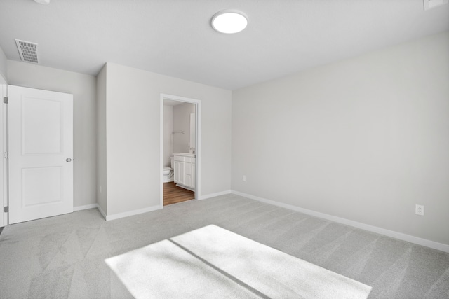 unfurnished bedroom featuring carpet, connected bathroom, visible vents, and baseboards