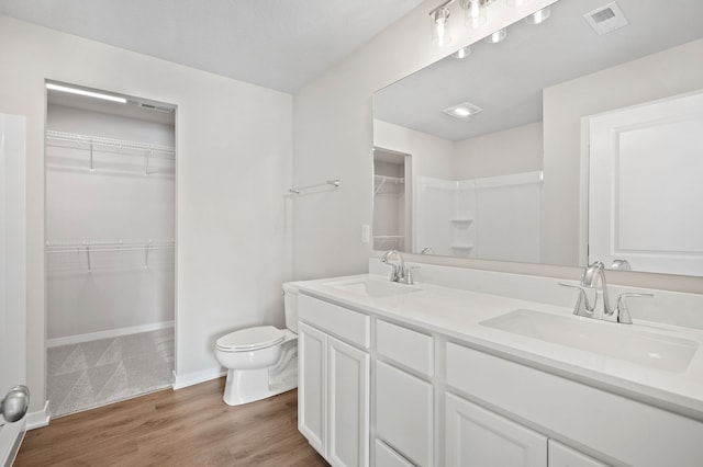 full bathroom featuring toilet, double vanity, a sink, and visible vents