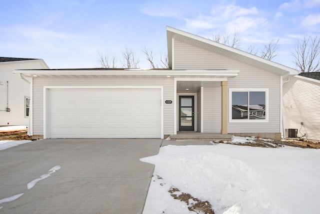 mid-century home featuring concrete driveway, an attached garage, and central air condition unit