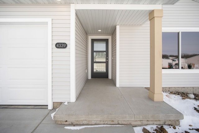 snow covered property entrance featuring a garage