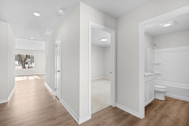 corridor featuring light wood-style flooring and baseboards