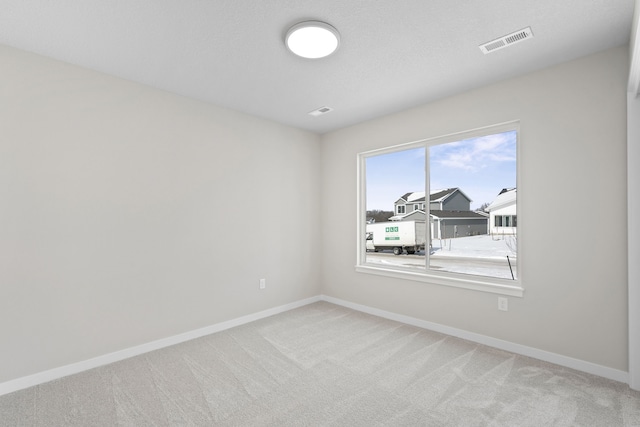 carpeted spare room with visible vents and baseboards