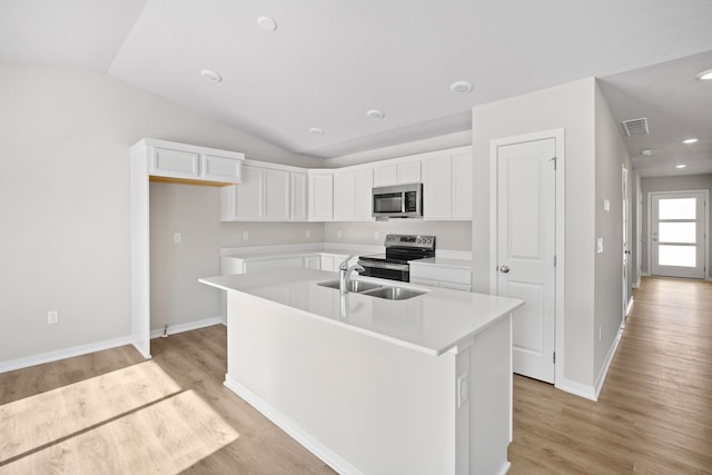 kitchen featuring appliances with stainless steel finishes, white cabinets, light countertops, and an island with sink