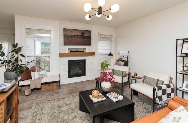 living room with wood-type flooring, an inviting chandelier, and a fireplace