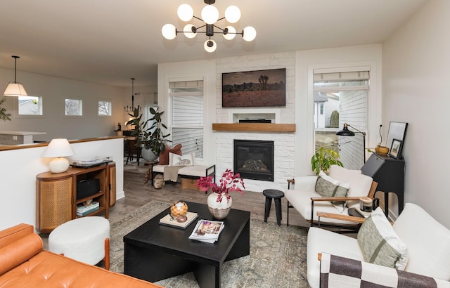 living room with hardwood / wood-style flooring, a stone fireplace, and an inviting chandelier