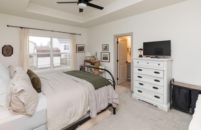 bedroom with ceiling fan, light colored carpet, and a raised ceiling