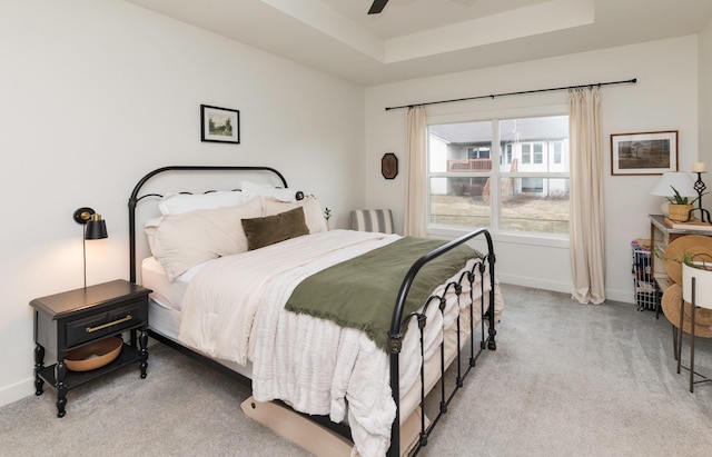 carpeted bedroom featuring a raised ceiling and ceiling fan