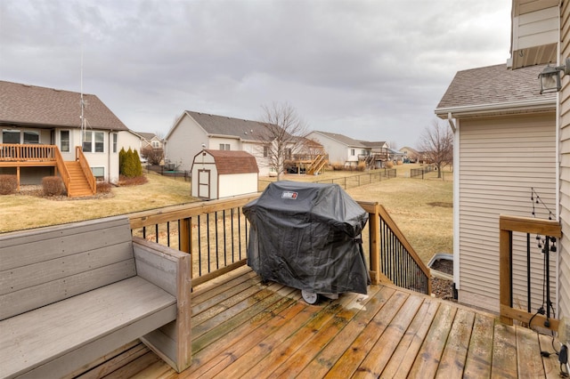 wooden terrace featuring a grill, a lawn, and a storage unit