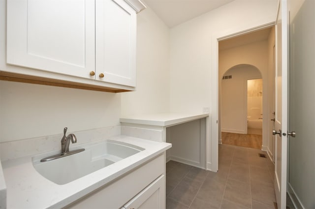 kitchen with white cabinetry, light stone countertops, sink, and light tile patterned floors