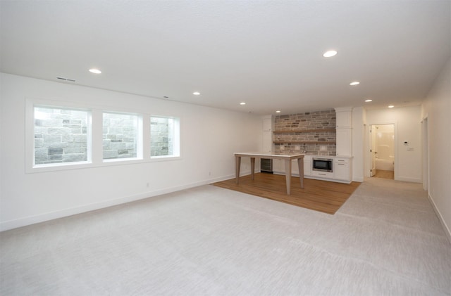 unfurnished living room with light colored carpet and a fireplace