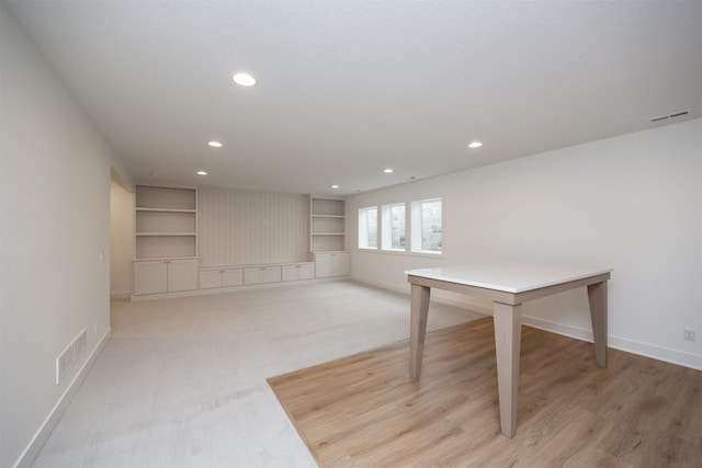 basement featuring light carpet and built in features