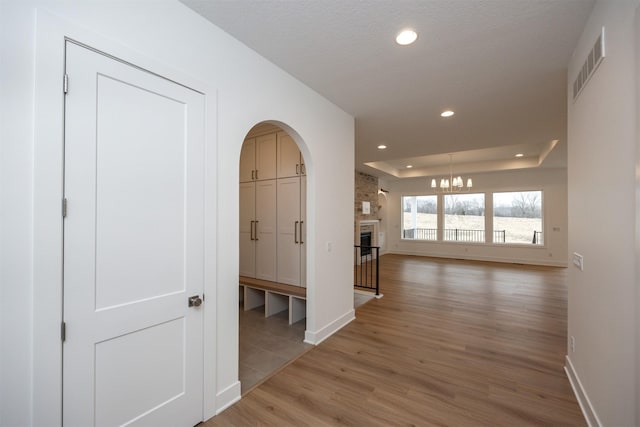 hall featuring hardwood / wood-style flooring, a raised ceiling, and a textured ceiling