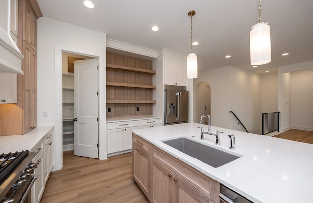 kitchen featuring sink, decorative light fixtures, light wood-type flooring, high quality appliances, and white cabinets