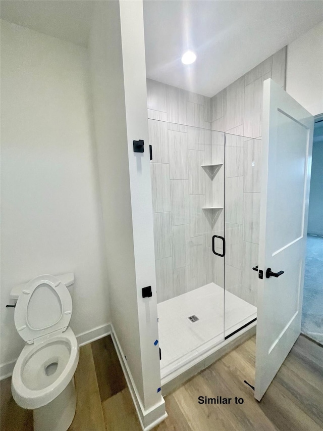 bathroom featuring hardwood / wood-style flooring, toilet, and a shower with door