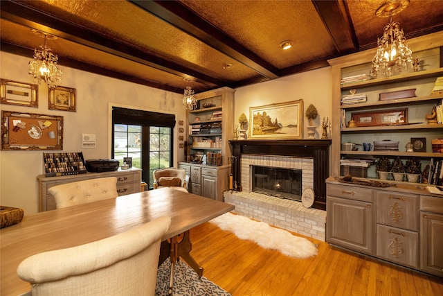 dining space featuring beamed ceiling, built in features, hardwood / wood-style floors, and a brick fireplace