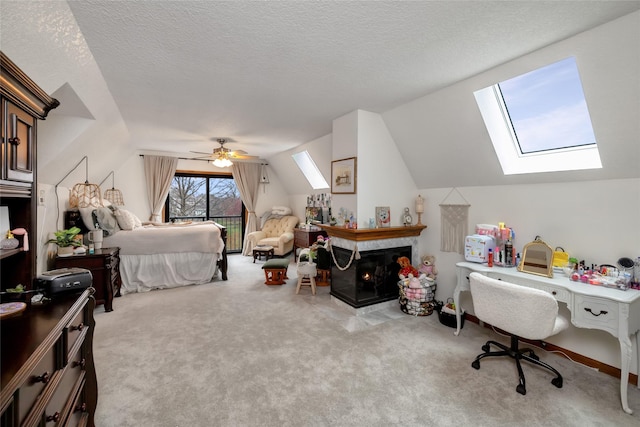 carpeted bedroom with ceiling fan, a textured ceiling, vaulted ceiling with skylight, and a multi sided fireplace