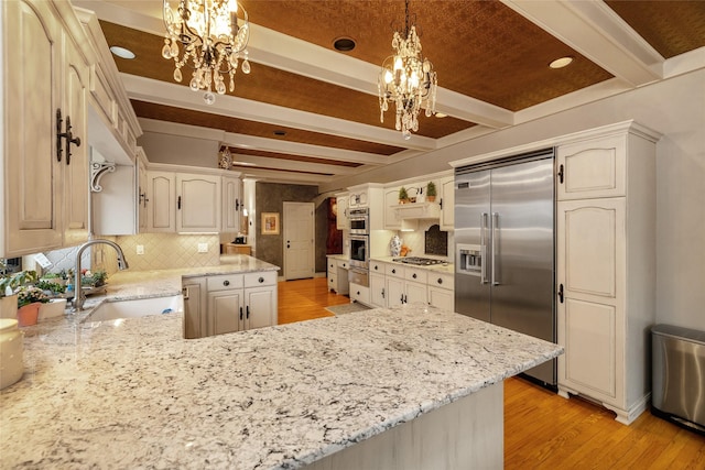 kitchen with sink, decorative light fixtures, appliances with stainless steel finishes, kitchen peninsula, and a notable chandelier