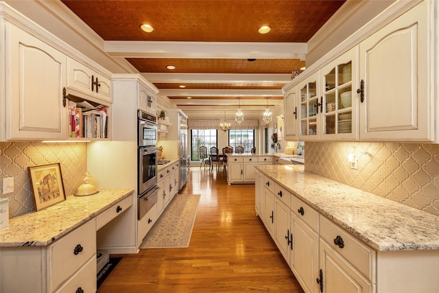 kitchen featuring white cabinetry, hanging light fixtures, light stone counters, light hardwood / wood-style floors, and beam ceiling