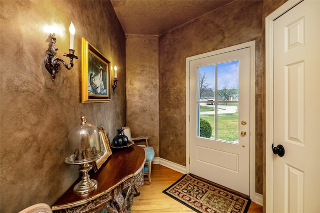 doorway to outside with wood-type flooring and a textured ceiling