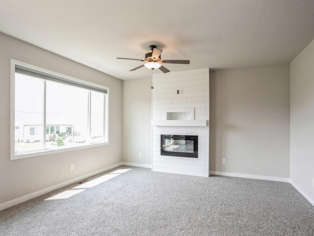 unfurnished living room featuring ceiling fan, carpet flooring, a fireplace, and a textured ceiling